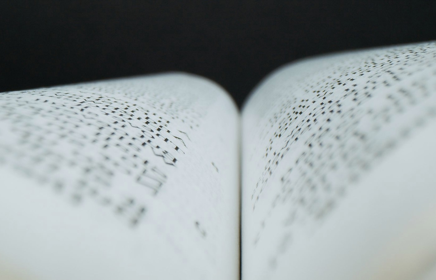 Extreme macro of a newsprint race page, the columns dissolved into texture with no legible word