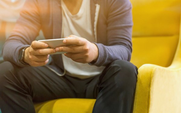 Adult hands holding a switched-off smartphone while seated in a grandstand