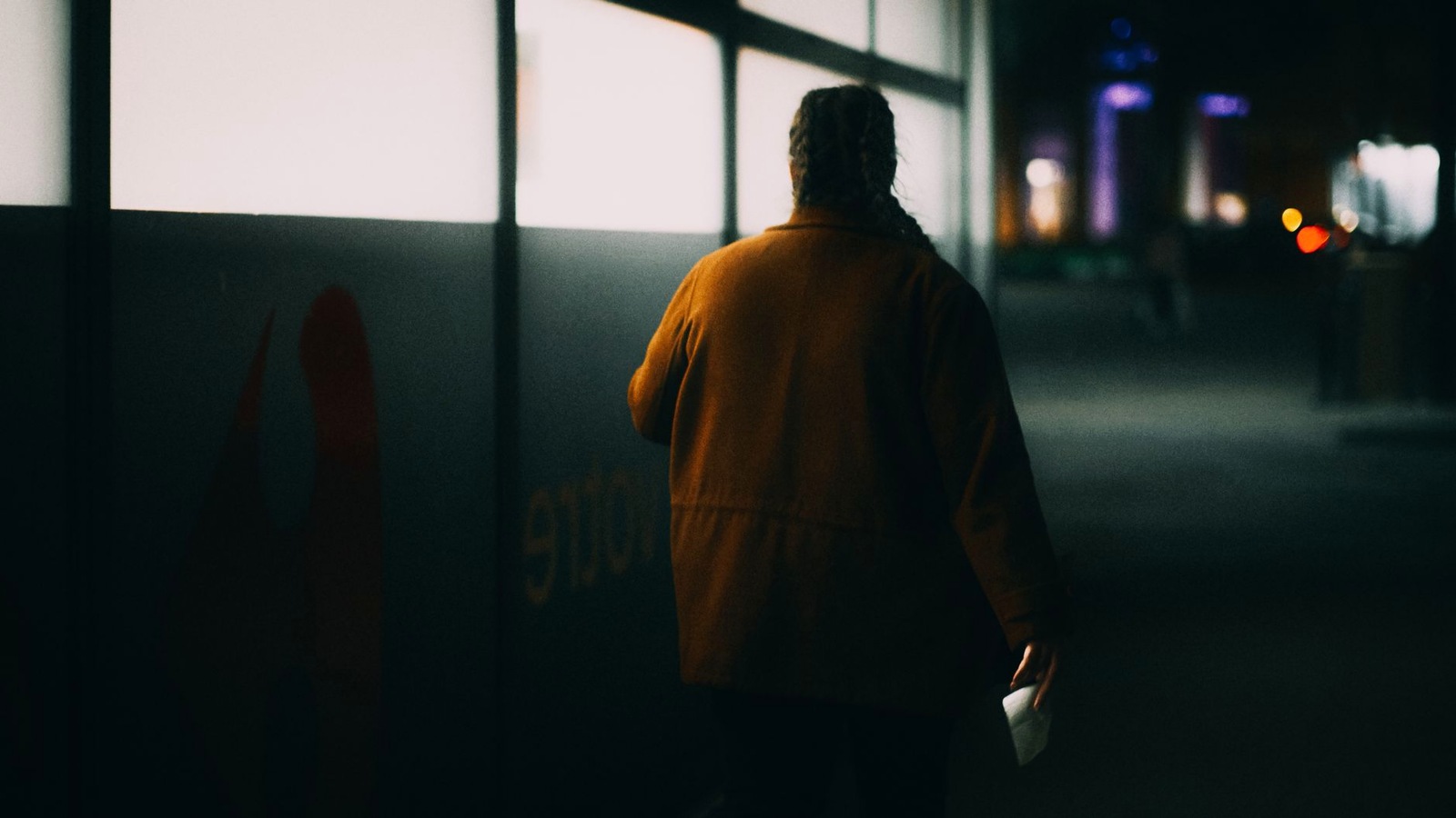 A single adult walking away across an emptying racecourse concourse at dusk